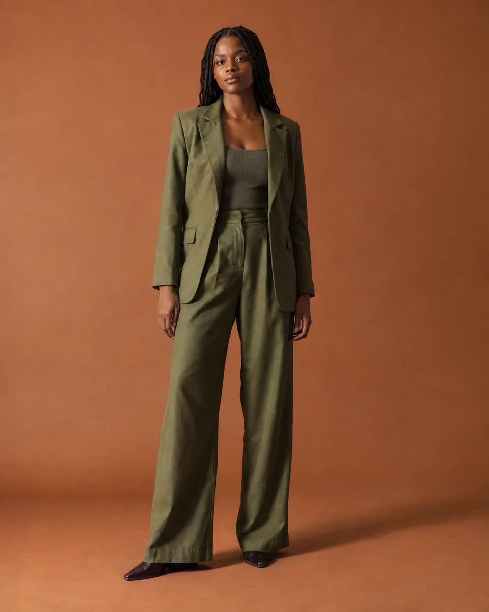Mulher adulta com roupa verde-oliva em um estúdio terracota.